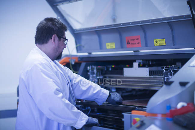 Hombre con bata de laboratorio en el lugar de trabajo - foto de stock