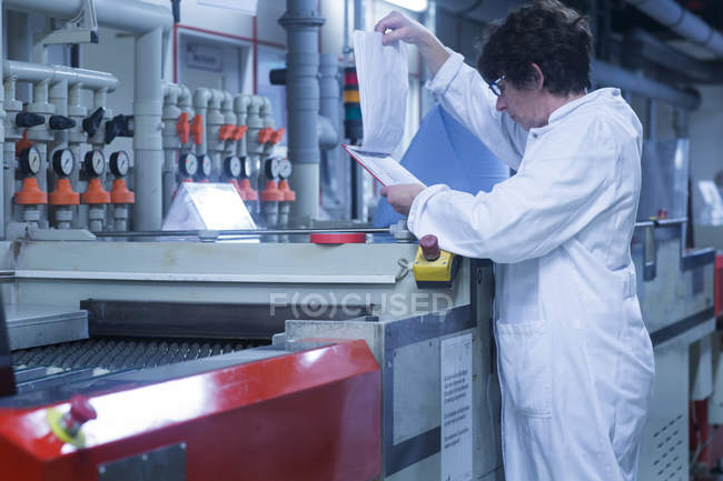 Woman in lab coat checking results — Stock Photo