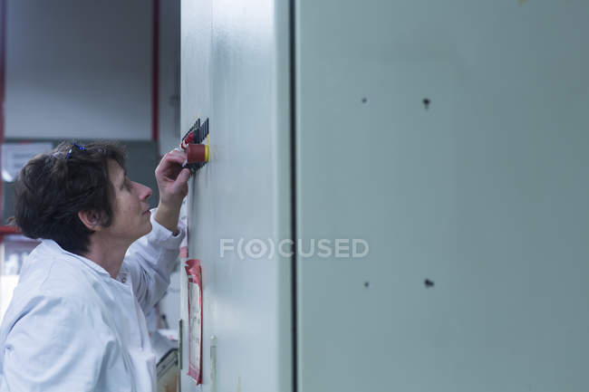 Woman in lab coat adjusting equipment — Stock Photo