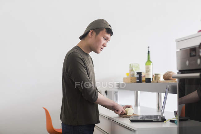 Hombre picando verduras en el mostrador de cocina - foto de stock