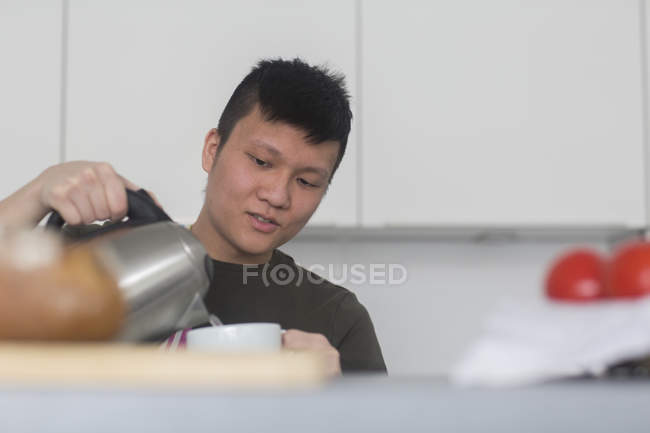 Uomo versando acqua bollente alla tazza di tè — Foto stock