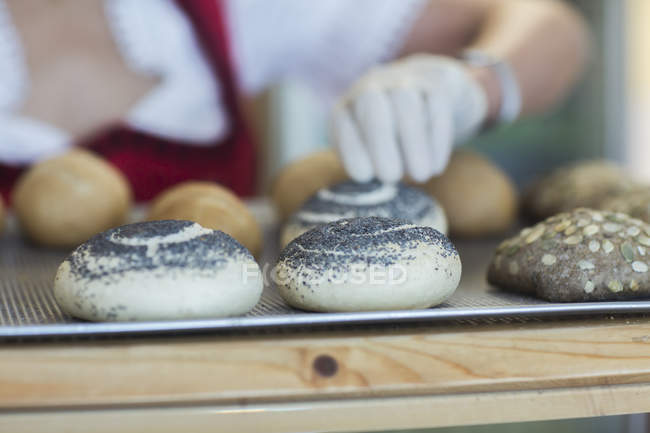Panadería manos de los trabajadores la colocación de bollos en el mostrador - foto de stock