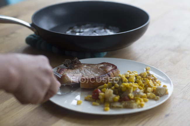 Personne coupant steak sur assiette — Photo de stock