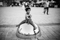 Маленькая девочка сидит на зеркальном шаре — стоковое фото