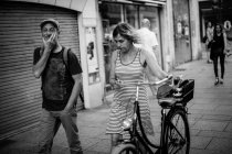 Donna che cammina sul marciapiede con bicicletta in mano — Foto stock