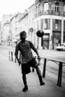 Мужчина пинает футбольный мяч на городской улице — стоковое фото