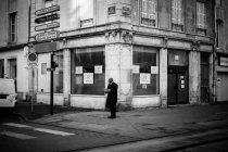 Homem de casaco preto em pé no cruzamento — Fotografia de Stock