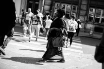 Femme marchant en robe noire dans la rue — Photo de stock