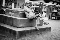 Mann sitzt auf Steinumrandung — Stockfoto