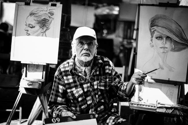 Bearded man drawing portraits — Stock Photo