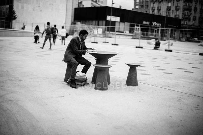 Mann sitzt auf Tisch und schreibt in Notizblock — Stockfoto