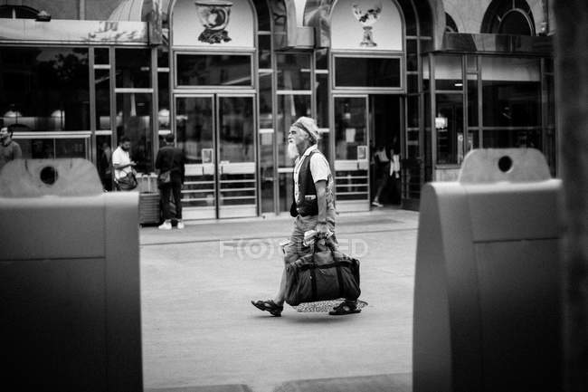 Senior man walking on street with handbag — Stock Photo