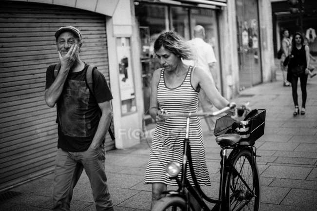 Женщина ходит по тротуару с велосипедом в руках — стоковое фото