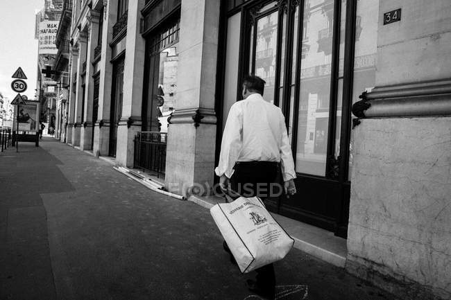 Homem andando na calçada com saco na mão — Fotografia de Stock