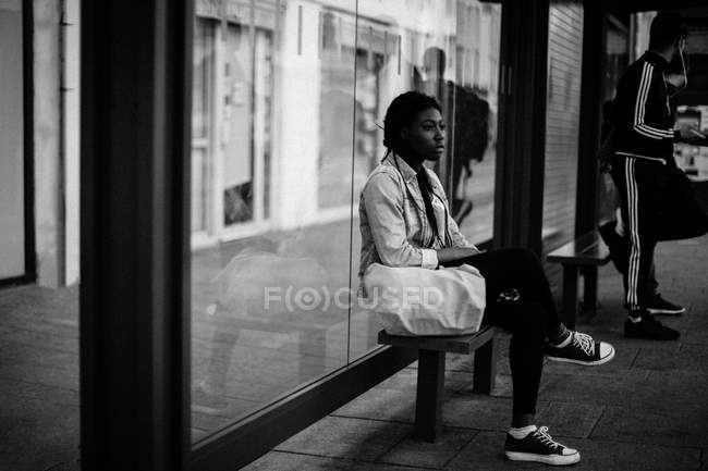 Frau sitzt an Straßenbahnhaltestelle — Stockfoto