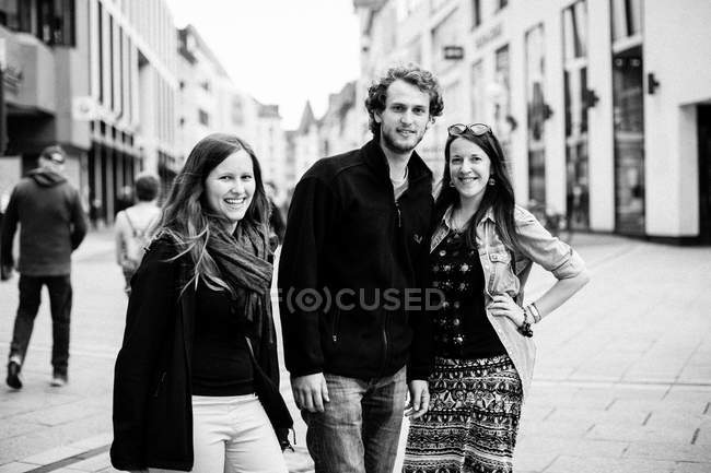 Hombre y dos mujeres de pie en la calle - foto de stock