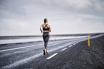 Mulher correndo em estrada deserta — Fotografia de Stock