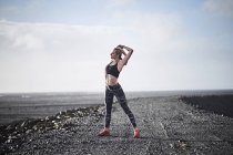 Woman stretching on deserted unmade road — Stock Photo