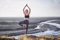 Mulher praticando ioga por estrada deserta — Fotografia de Stock