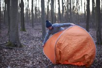 Man puts up tent in woods — Stock Photo