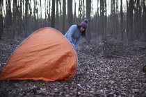Woman puts up a tent in woods — Stock Photo