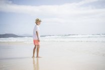 Niño de pie en la playa - foto de stock
