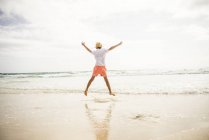 Хлопчик, стрибнувши на пляж — стокове фото