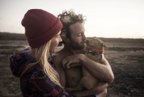 Couple holding dog on beach — Stock Photo