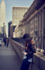 Mulher em jeans e chapéu esperando contra grades — Fotografia de Stock
