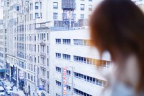 Mujer sentada junto a la ventana en el apartamento de Nueva York - foto de stock