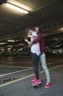Homem abraçando namorada enquanto de pé no skate — Fotografia de Stock