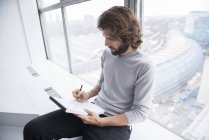 Businessman writing notes on pad — Stock Photo
