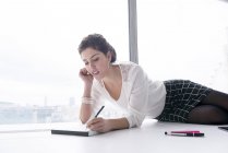 Businesswoman making notes on pad — Stock Photo