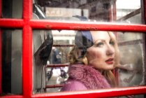 Mujer de pie en el quiosco telefónico en Londres - foto de stock
