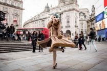 Woman twirling around by statue of Eros — Stock Photo