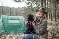 Dame sitzt mit Hund und genießt Wildnis — Stockfoto