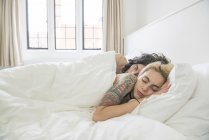 Tattooed couple sleeping in bed — Stock Photo