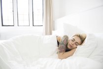 Mulher tatuada dormindo na cama — Fotografia de Stock