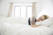 Tätowierte Frau schläft im Bett — Stockfoto