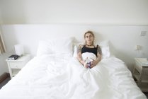 Жінка лежить в ліжку і насолоджується чашкою чаю — стокове фото