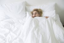Женщина в постели с одеялом поднял до подбородка — стоковое фото