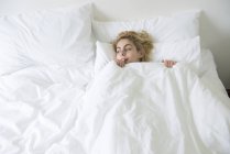 Femme au lit avec couette tirée vers le haut au menton — Photo de stock