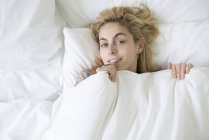 Donna a letto con piumone tirato fino al mento — Foto stock