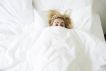 Frau im Bett mit Bettdecke bis zum Kinn hochgezogen — Stockfoto