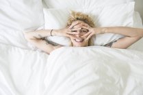 Mulher deitada na cama e cobrindo rosto com as mãos — Fotografia de Stock