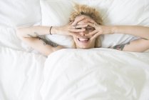 Donna sdraiata a letto e che copre il viso con le mani — Foto stock
