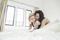 Tattooed couple cuddling on bed — Stock Photo