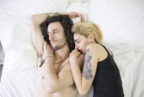 Tatuado casal abraçando na cama — Fotografia de Stock