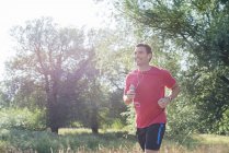 Homme jogging à travers le parc — Photo de stock