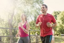 Homme et femme jogging à travers le parc — Photo de stock